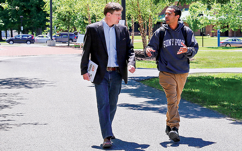 Professor John Marsh walks with student near the Student Center