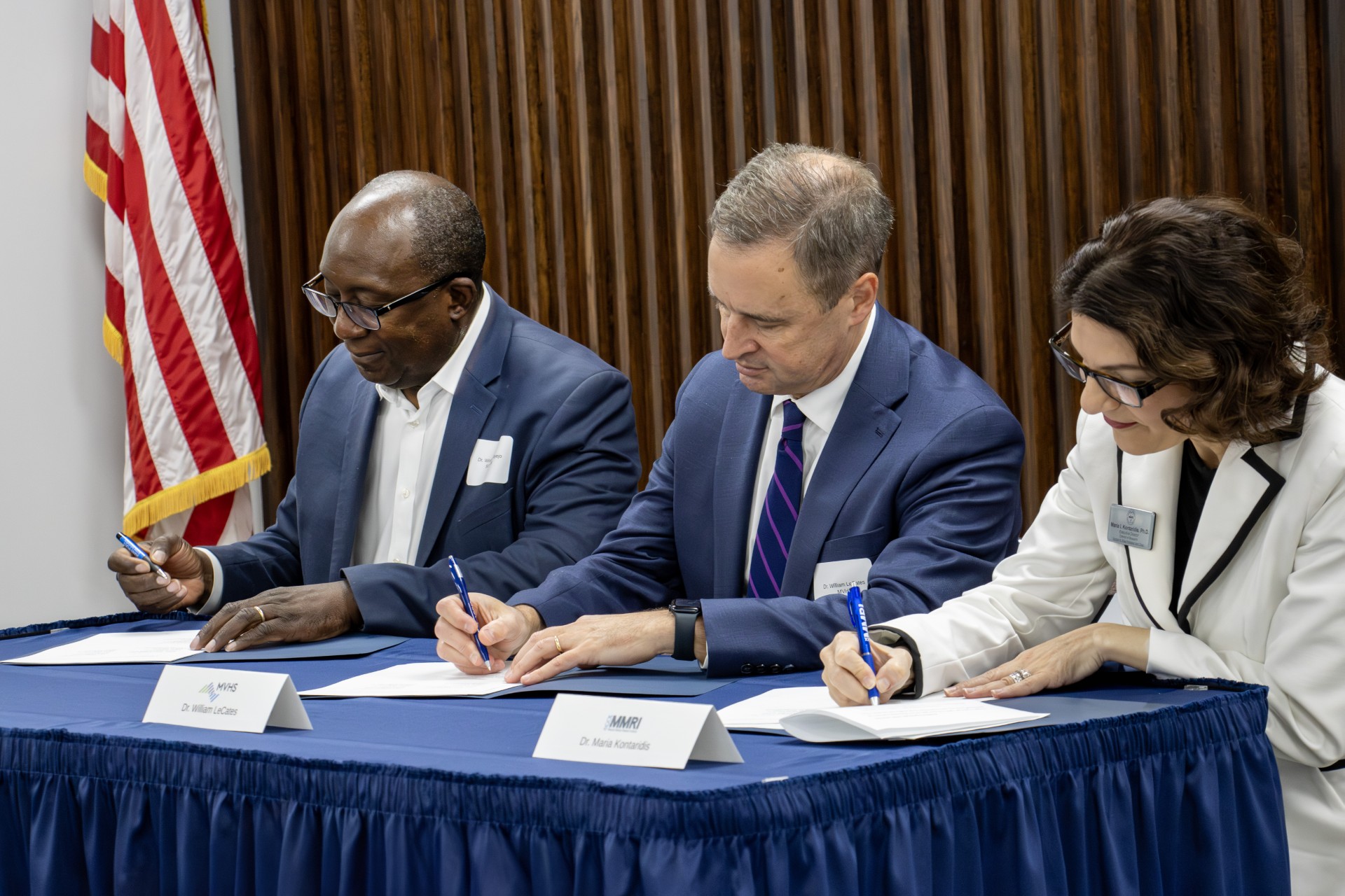 Three people signing documents during a SUNY Poly partnership agreement