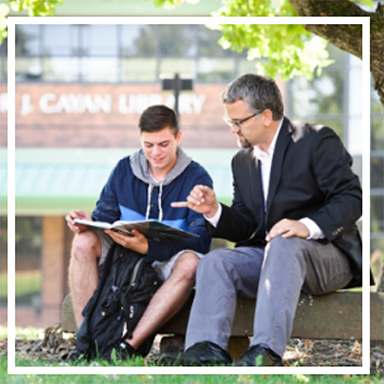 student and teacher looking at book