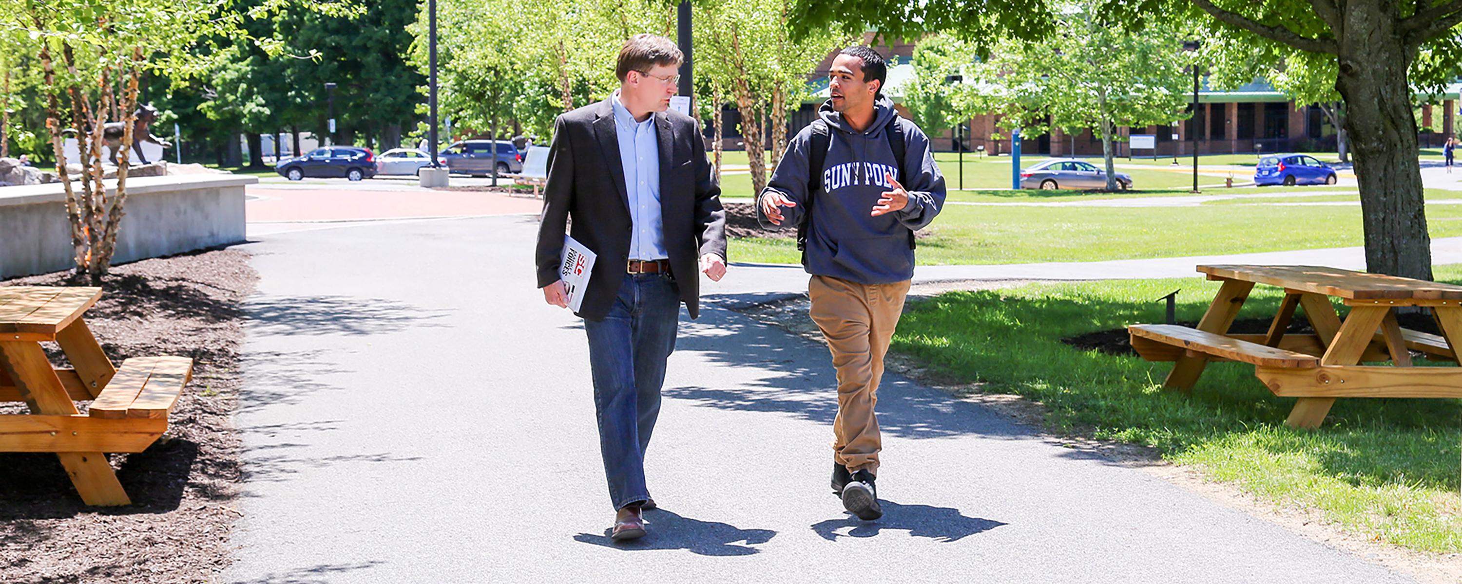 student and professor walking on campus image
