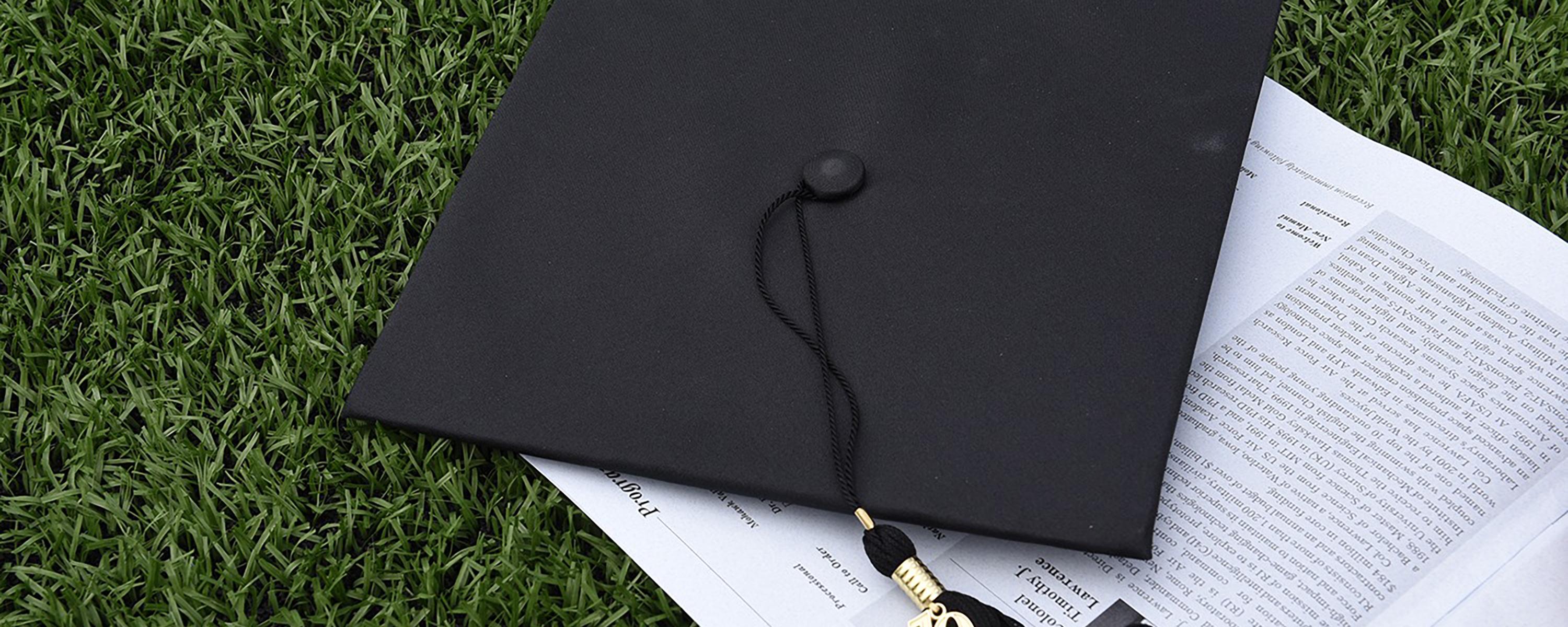 image of graduation cap and program on turf