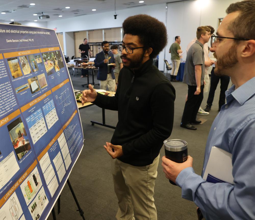 Student explains research that is on poster to member of SUNY Poly community