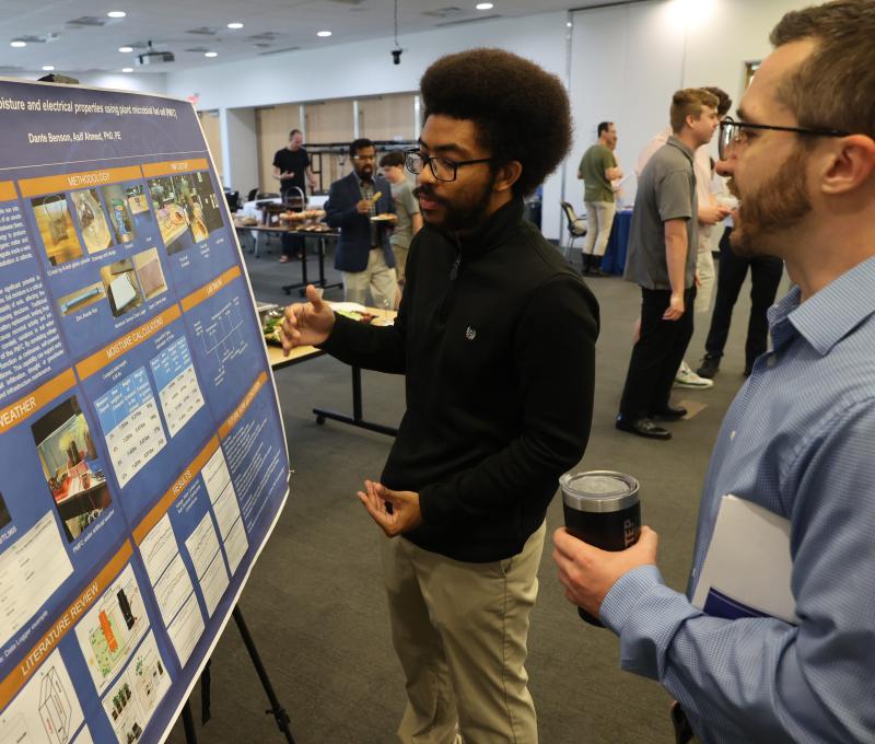 Student explains research that is on poster to member of SUNY Poly community
